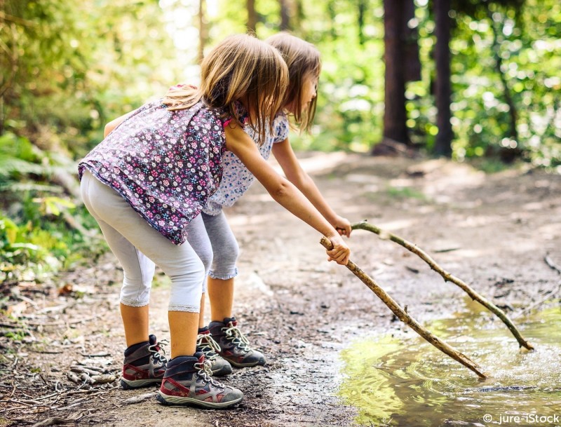 AUBEL_petites filles jouant avec un bois dans l'eau©_jureistock2020